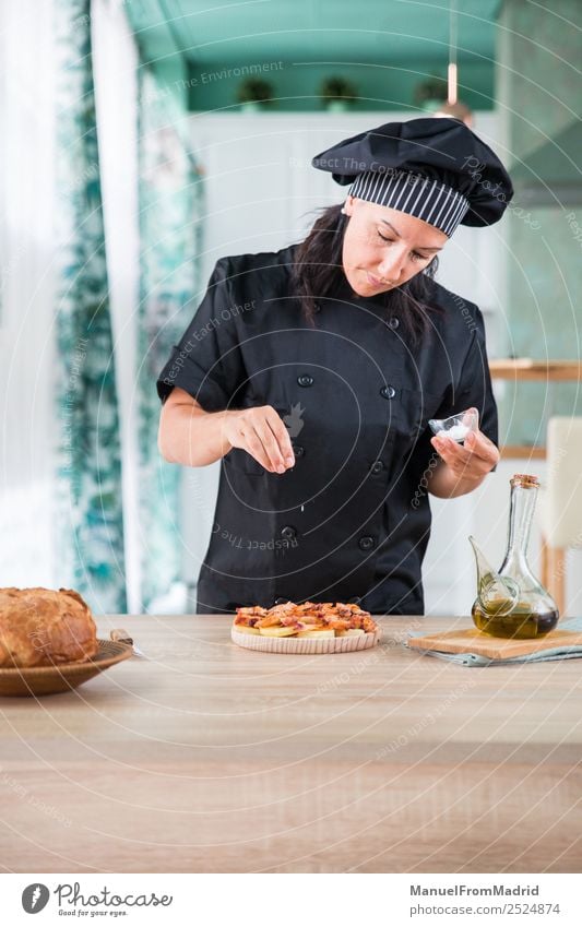 woman chef seasoning a dish Herbs and spices Nutrition Plate Table Kitchen Human being Woman Adults Hand Hat Wood Modern cook adding salt Octopus galician pulpo