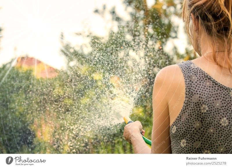 a woman waters her garden with a garden hose Human being Feminine Woman Adults 1 Environment Nature Garden Work and employment Climate "garden soak Summer ardor