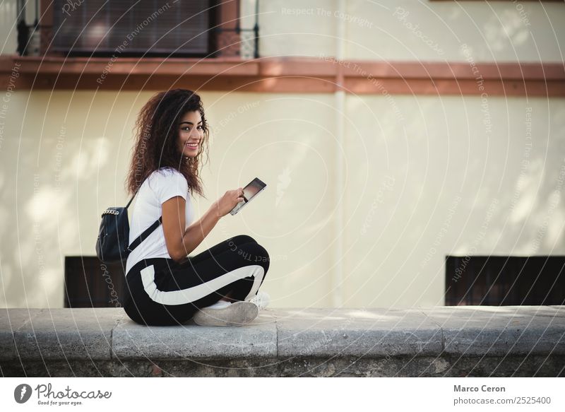 beautiful young woman with backpak and casual dressed using her tablet in the street african backpack bag black brown hair curly hair cute device enjoying happy