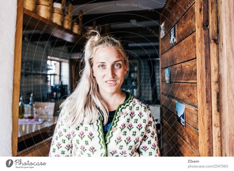 Young woman in alpine hut Style Feminine Youth (Young adults) 18 - 30 years Adults Hut Costume Cardigan Blonde Long-haired Work and employment Smiling Laughter