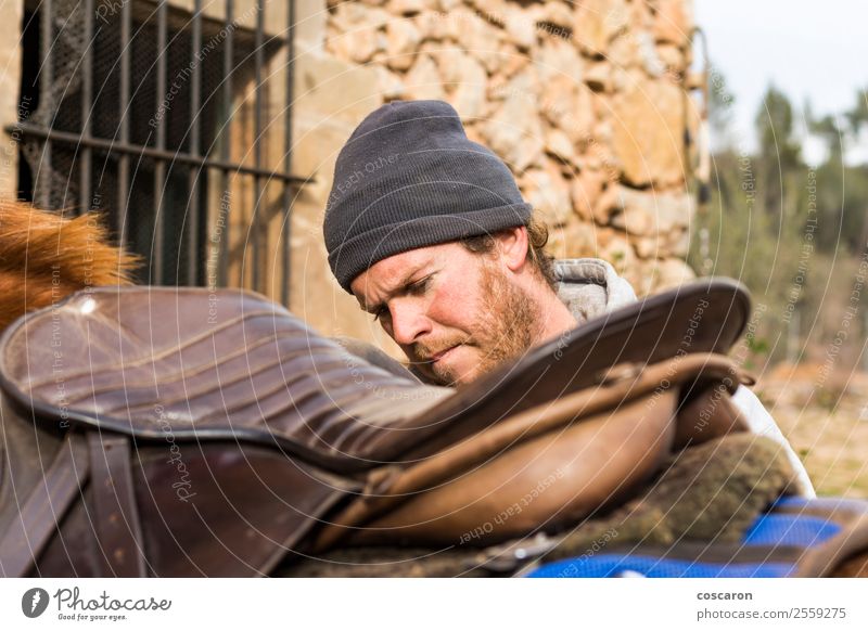 Portrait of a young male adjusting the saddle on his horse Lifestyle Beautiful Leisure and hobbies Ride Equestrian sports Rope Human being Masculine Young man