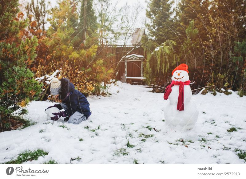 happy kid girl making snow man on Christmas Joy Leisure and hobbies Playing Vacation & Travel Winter Snow Garden Child Nature Weather Park Clothing Make Snowman