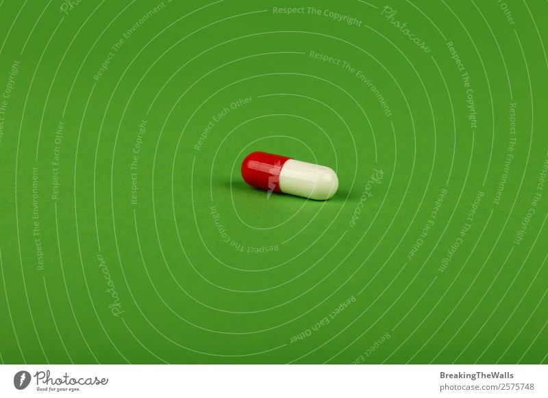 Close up one red and white gel cap pill of medicine on green Healthy Health care Medical treatment Intoxicant Medication Natural Soft Green Red White Colour