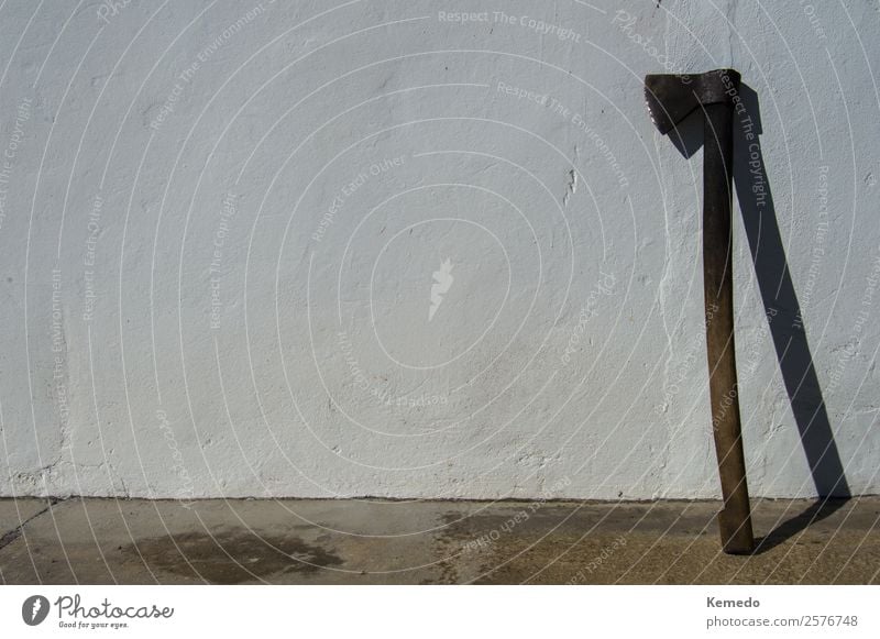 Old and dirty axe resting on a white wall with copy space. Life Harmonious Adventure Summer Mountain Garden Professional training Work and employment Gardening