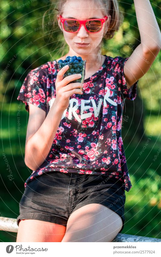 Happy girl enjoying eating the fresh blueberries outdoors Food Fruit Dessert Nutrition Eating Vegetarian diet Diet Glass Lifestyle Summer Garden Human being