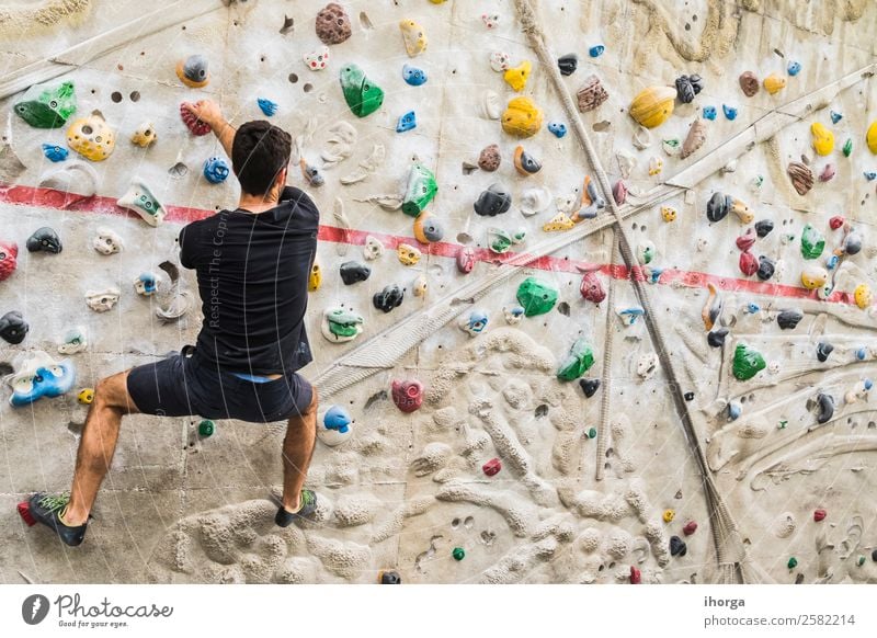 A Man practicing rock climbing on artificial wall indoors Lifestyle Joy Leisure and hobbies Sports Climbing Mountaineering Young man Youth (Young adults) Adults