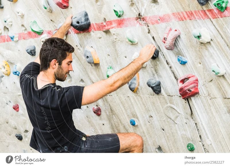 A Man practicing rock climbing on artificial wall indoors Lifestyle Joy Leisure and hobbies Sports Climbing Mountaineering Young man Youth (Young adults) Adults