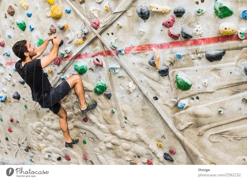 A Man practicing rock climbing on artificial wall indoors Lifestyle Joy Leisure and hobbies Sports Climbing Mountaineering Young man Youth (Young adults) Adults