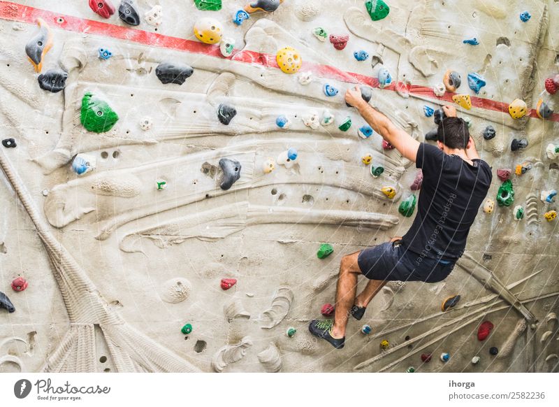 A Man practicing rock climbing on artificial wall indoors Lifestyle Joy Leisure and hobbies Sports Climbing Mountaineering Adults Hand Fingers Feet 1