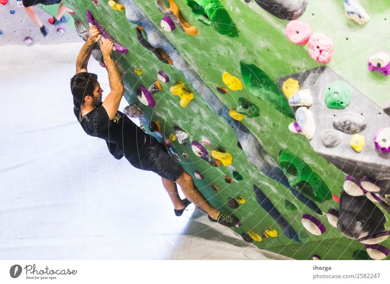 A Man practicing rock climbing on artificial wall indoors Lifestyle Joy Leisure and hobbies Sports Climbing Mountaineering Young man Youth (Young adults) Adults