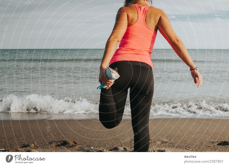 Leg stretching in front of the sea. Sports girl. Lifestyle Body Athletic Fitness Wellness Leisure and hobbies Beach Sports Training Jogging Human being Feminine