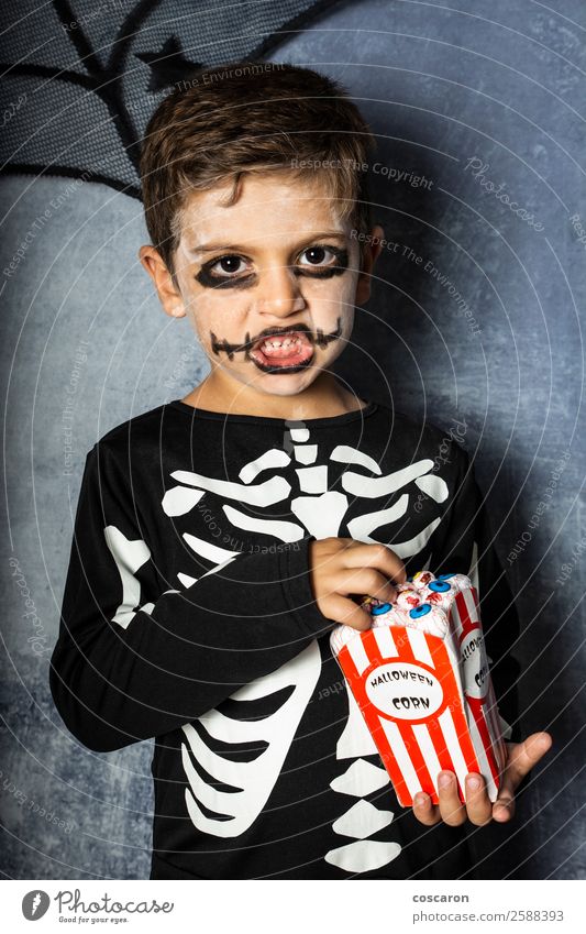 Little kid in a skeleton costume eating fake eyes on Halloween Joy Happy Face Make-up Feasts & Celebrations Carnival Hallowe'en Fairs & Carnivals Child