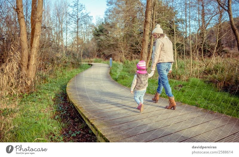 Back view of mother and daughter walking over a wooden pathway Lifestyle Joy Happy Calm Leisure and hobbies Freedom Winter Child Woman Adults Parents Mother