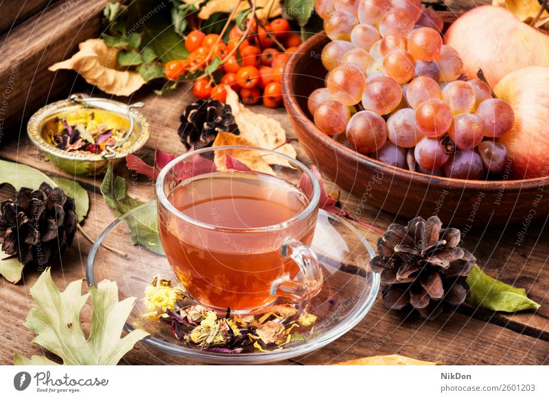 Cup of tea with autumn leaves drink fall cup hot rustic warm season wooden fruit table grape vintage beverage mug food morning yellow concept leaf glass still