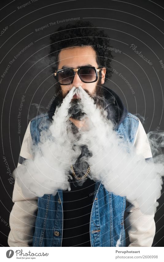 Young man with sunglasses blowing a cloud of smoke. Lifestyle Elegant Happy Technology Human being Man Adults Clouds Sunglasses Beard Black Cigarette Electronic