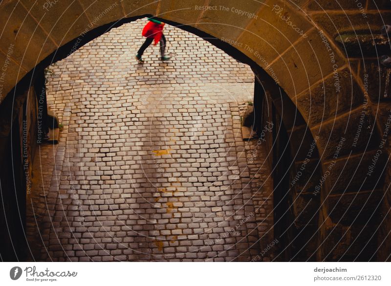 On the way is a person with a red jacket who is tied up. She is passing a paved archway. You can only see her feet. Joy Trip Feminine Young woman