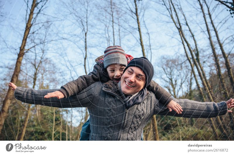 Man giving piggyback ride to happy kid in the forest Lifestyle Joy Happy Leisure and hobbies Playing Winter Child Boy (child) Adults Parents Father