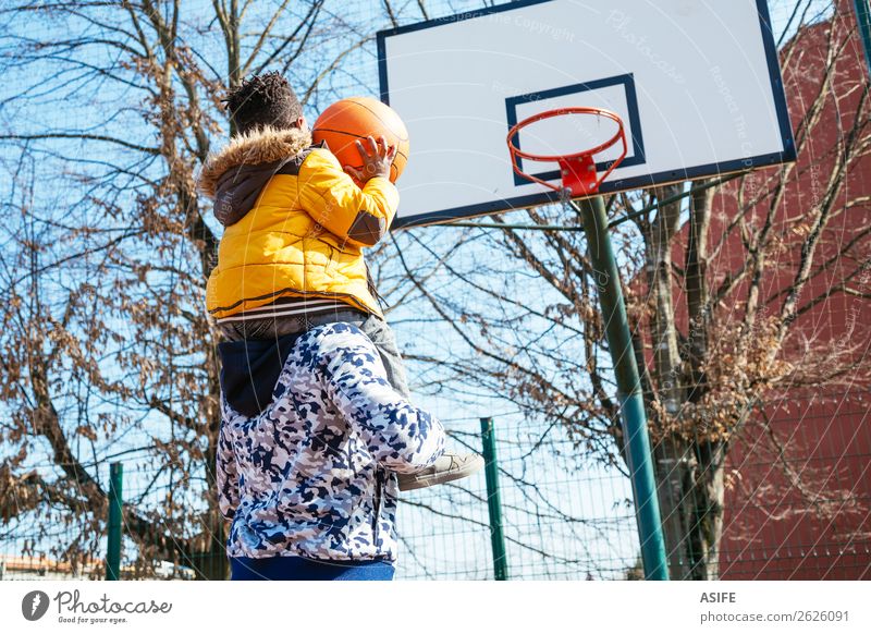 Happy father holding on shoulders his little son to help him to score a basket Joy Relaxation Leisure and hobbies Playing Winter Sports School Boy (child)