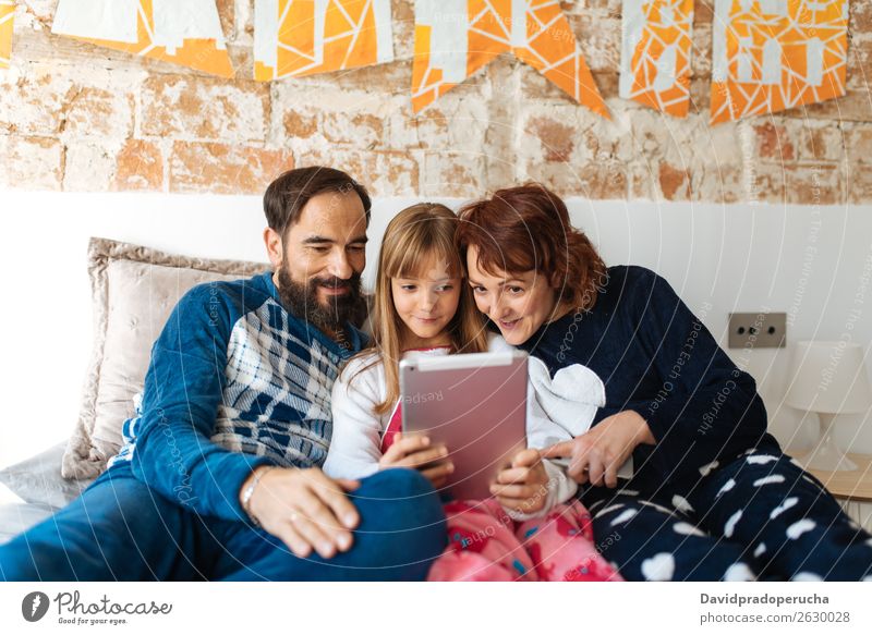 Couple relaxed at home in bed with their little daughter on the mobile phone and tablet Affection Bed Bedroom Wife Husband Daughter Child Mobile Telephone