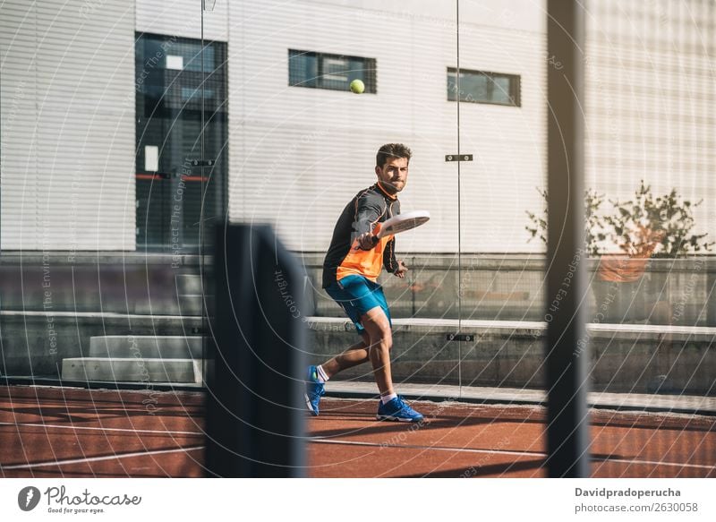 Man playing padel paddel Glass Court building Joy Leisure and hobbies Exterior shot Shot Match padel tennis Playing Tennis padel class padel court Net Equipment