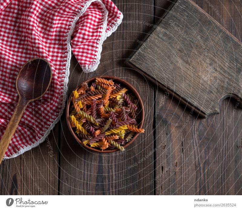 raw pasta in brown clay bowl on wooden table Nutrition Diet Bowl Spoon Brown Yellow Red Colour Tradition colorful cooking Dish dry food Fusilli healthy Heap