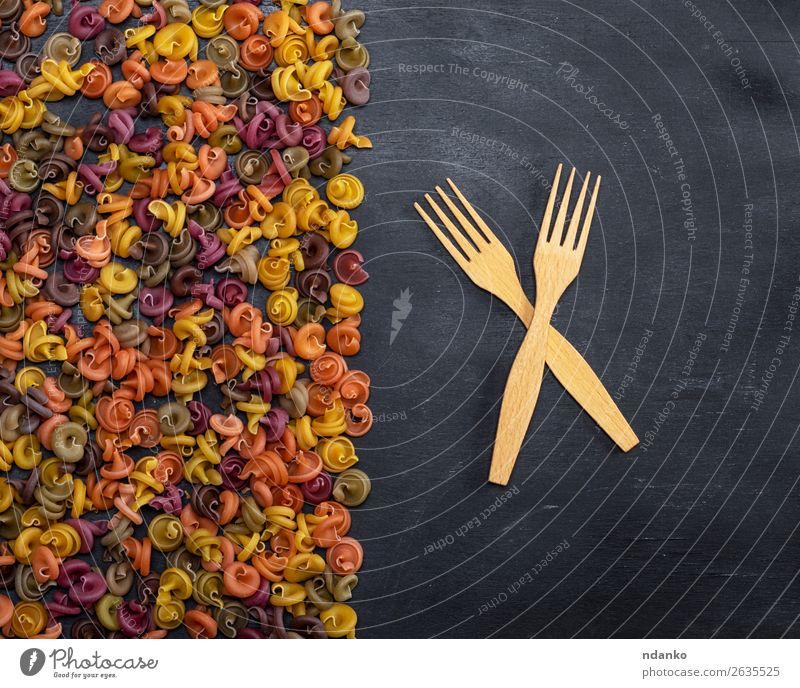 pasta multicolored spiral of wheat flour on a black background Dough Baked goods Nutrition Lunch Dinner Fork Restaurant Wood Fresh Natural Brown Yellow Red