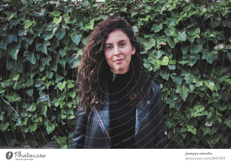 Portrait of a young woman wearing a leather jacket against a wall covered in greenery Lifestyle Happy Beautiful Face Human being Nature Plant Autumn Ivy Leaf