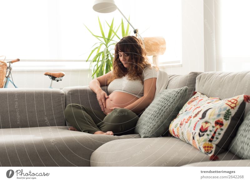 Pregnant woman touching her belly Lifestyle Happy Beautiful Leisure and hobbies Sofa Human being Baby Woman Adults Parents Mother Family & Relations Touch Love