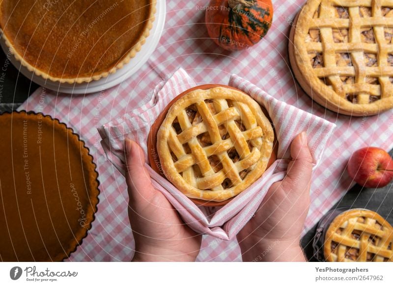 Apple pie held in hands over a table with many pies. Cake Dessert Candy Kitchen Feasts & Celebrations Thanksgiving Christmas & Advent Exceptional Sweet Many