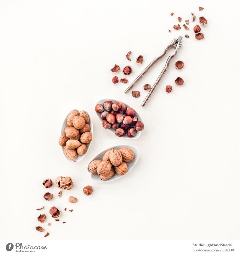 Variety of nuts and nutcracker Nutrition Eating Vegetarian diet Diet Plate Fresh Natural Brown White Colour Decline hazelnut hazelnuts Almond almonds walnut