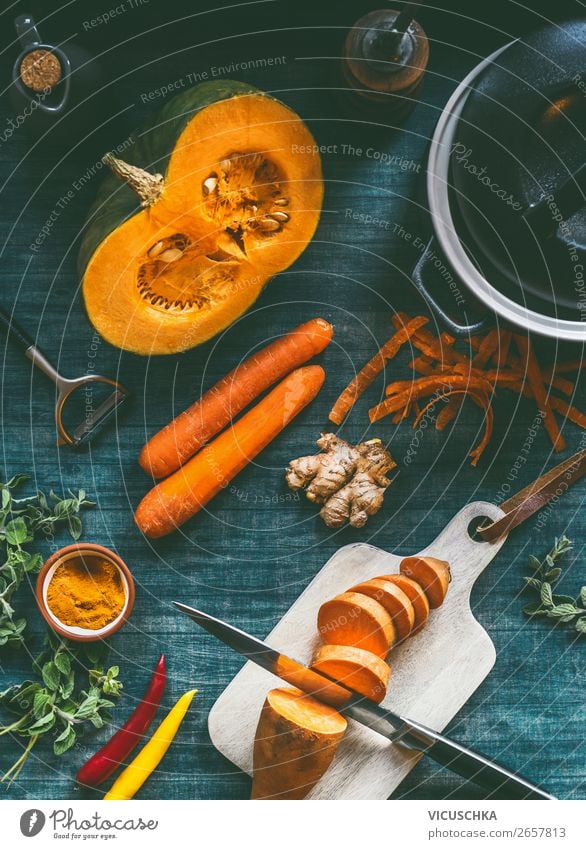 Ingredients for healthy soup or vegetables stew with orange color vegetarian ingredients : pumpkin, carrots, sweet potatoes , turmeric, ginger and chili on kitchen table background, top view.