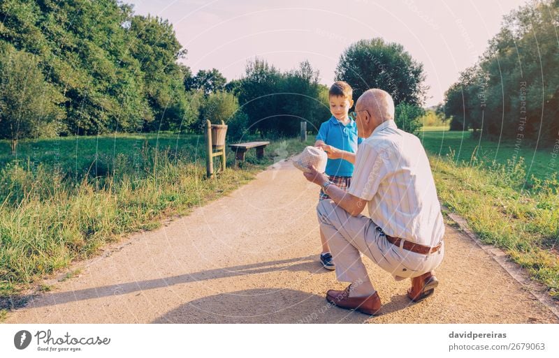 Grandfather showing his hat to grandchild outdoors Lifestyle Joy Happy Leisure and hobbies Playing Summer Child Boy (child) Man Adults Parents