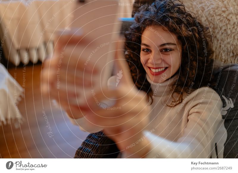 cheerful woman is taking a selfie Woman attractive beautiful blouse brazilian brown-haired camera caucasian cellphone cozy curly curly hair cute face female