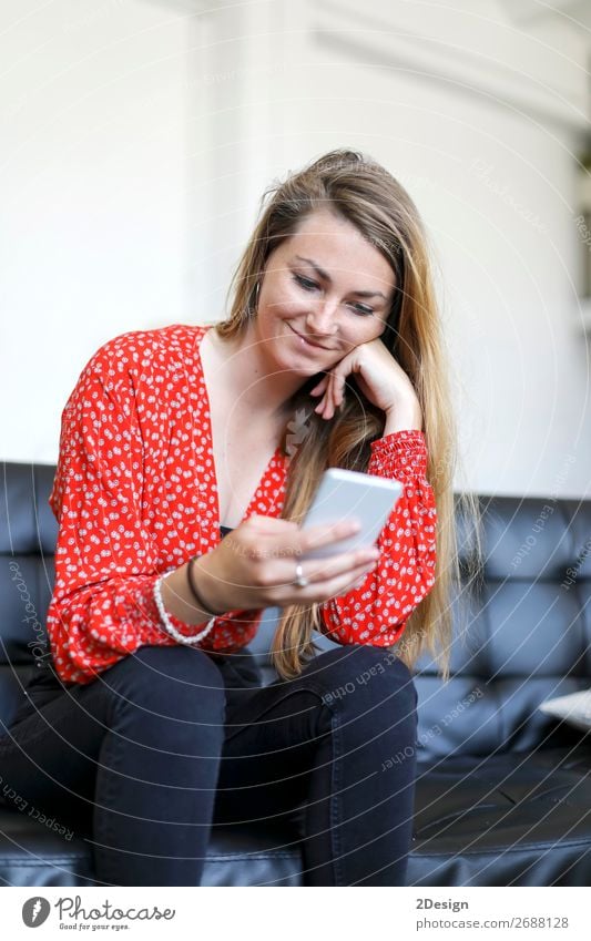 Blonde girl using a smartphone while sitting on leather sofa Beautiful Hair and hairstyles Sofa Living room Telephone Cellphone PDA Technology Human being