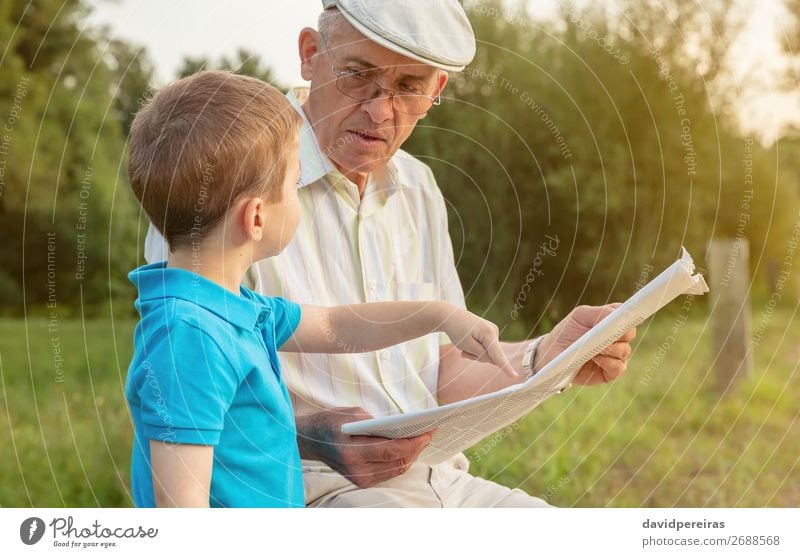 Senior man and child reading a newspaper outdoors Lifestyle Happy Leisure and hobbies Reading Child School Human being Boy (child) Man Adults Parents