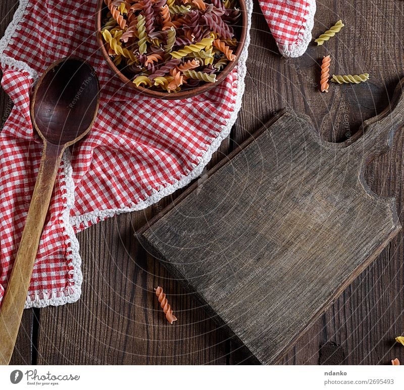 raw pasta fusilli on a brown wooden table Dough Baked goods Nutrition Italian Food Bowl Spoon Table Wood Retro Brown Yellow Red Colour Tradition colorful