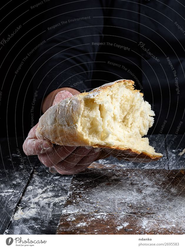 chef hand holds half baked white wheat flour bread Bread Nutrition Table Kitchen Human being Hand Fingers Wood Make Dark Fresh Brown Black White Tradition