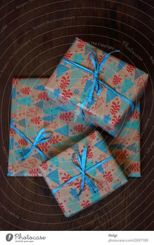 three wrapped gifts in christmassy patterned paper with blue bows lie on top of each other Feasts & Celebrations Christmas & Advent Birthday Packaging