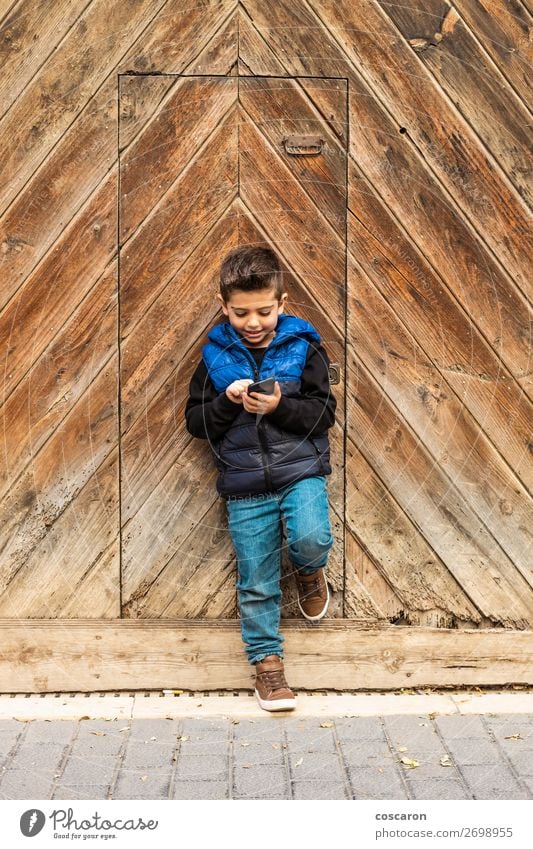 Little boy with a mibile phone with a wooden door background Lifestyle Design Beautiful Playing Vacation & Travel House (Residential Structure) Child Telephone