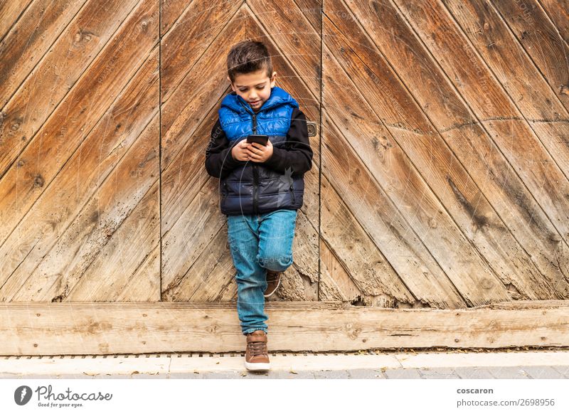 Little boy with a mibile phone with a wooden door background Beautiful Playing Vacation & Travel House (Residential Structure) Child Telephone Cellphone PDA