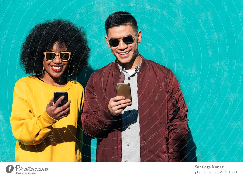 Two happy friends using the mobile in the street. Friendship Youth (Young adults) Mobile Black Mixed race ethnicity asian Chinese Group Telephone African