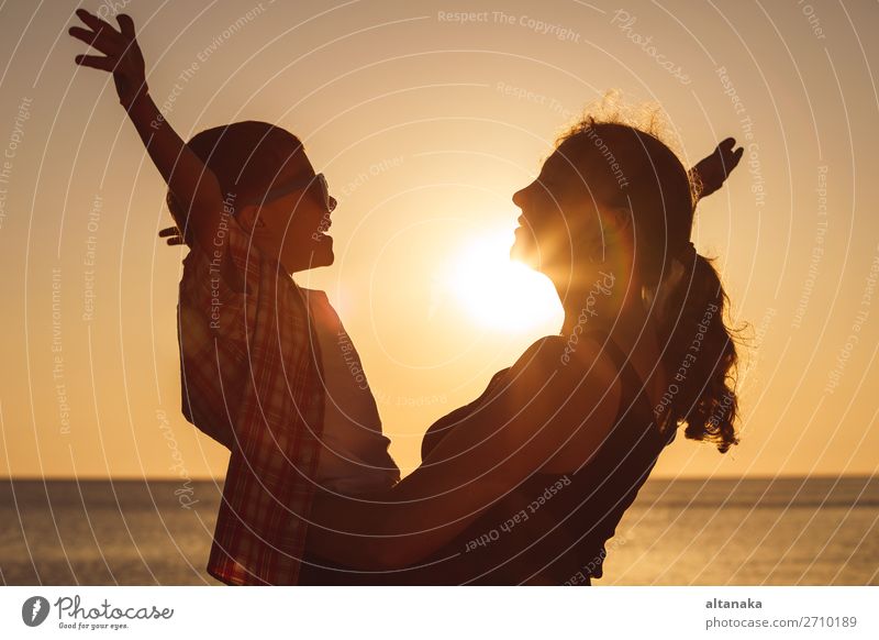 Mother and son playing on the beach at the sunset time. People having fun outdoors. Concept of happy vacation and friendly family. Lifestyle Joy Happy