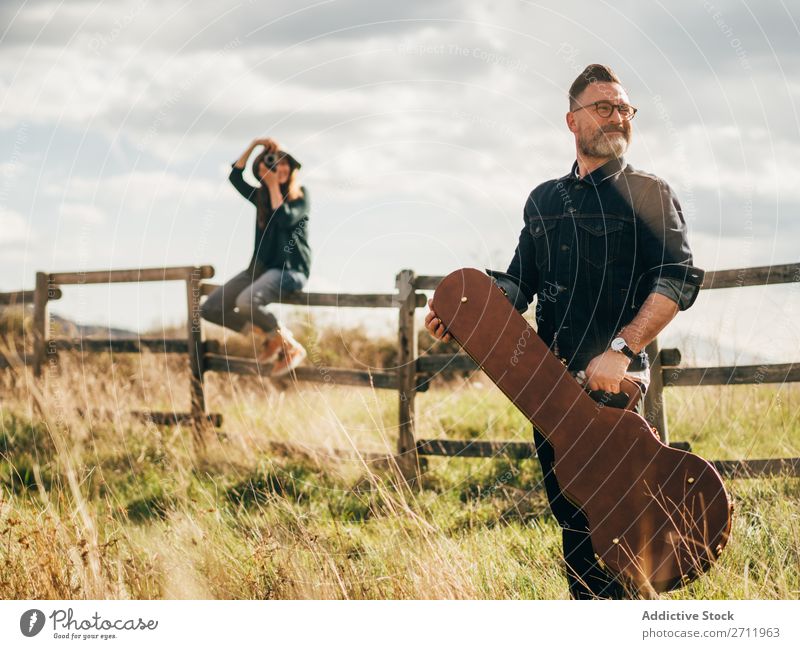 Woman taking shot of man with guitar Man Guitar Nature Musician Photographer To fall Sit Rural Fence Lifestyle Human being Summer Easygoing Acoustic handsome