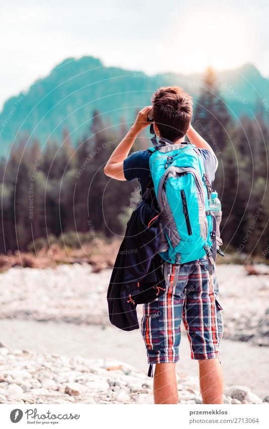 Young wanderer with backpack looks through a binoculars Lifestyle Leisure and hobbies Vacation & Travel Tourism Trip Summer Mountain Human being Boy (child)