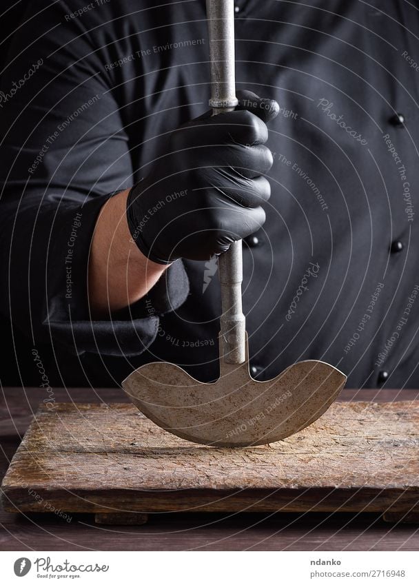 chef in black clothes holds metal old knife Knives Kitchen Work and employment Cook Man Adults Hand Gloves Metal Steel Make Black big blade board butcher