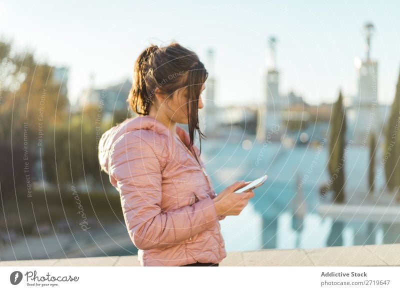 Pretty woman standing with smartphone on street Woman pretty PDA Park Happy Beautiful Telephone Youth (Young adults) Mobile Attractive Lifestyle Nature