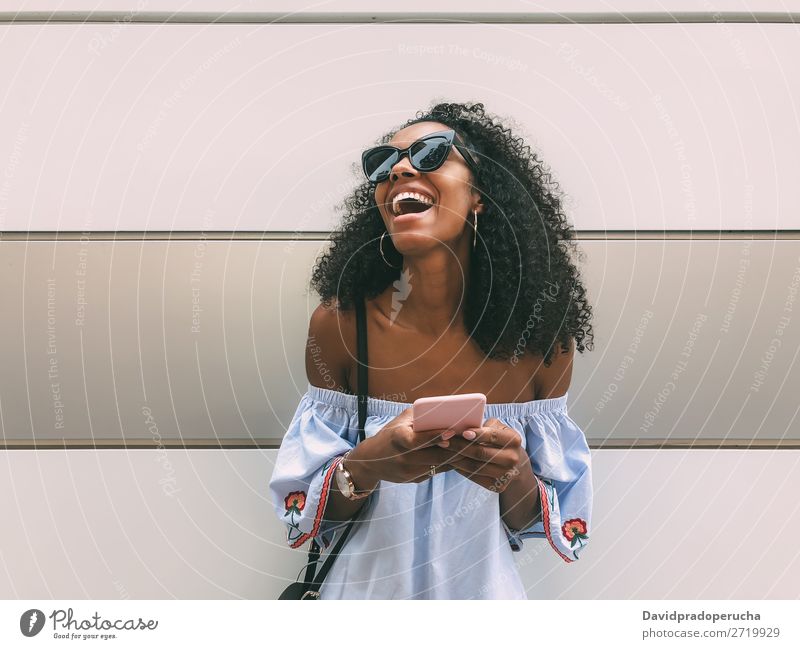 Cheerful black woman with mobile phone Woman Wall (building) Adults Easygoing PDA African Ethnic Cellphone Copy Space Youth (Young adults) Lifestyle pastel