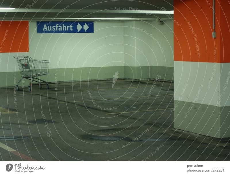 Underground car park from the inside. Exit sign. Parking marker, empty shopping trolley. Neon lights,. Dirty and ugly Underground garage Shopping Trolley