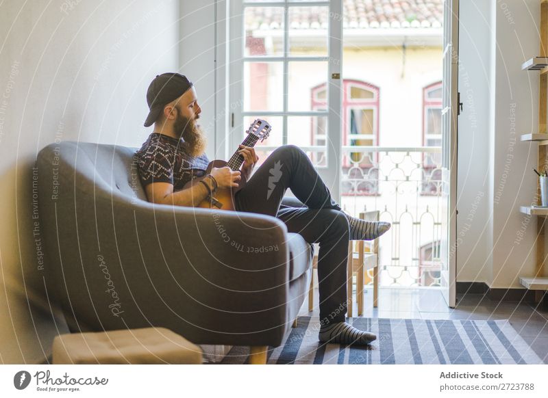 Man playing guitar in armchair Home Relaxation Adults bearded Sit Armchair Playing Guitar Musician Acoustic Easygoing Youth (Young adults)