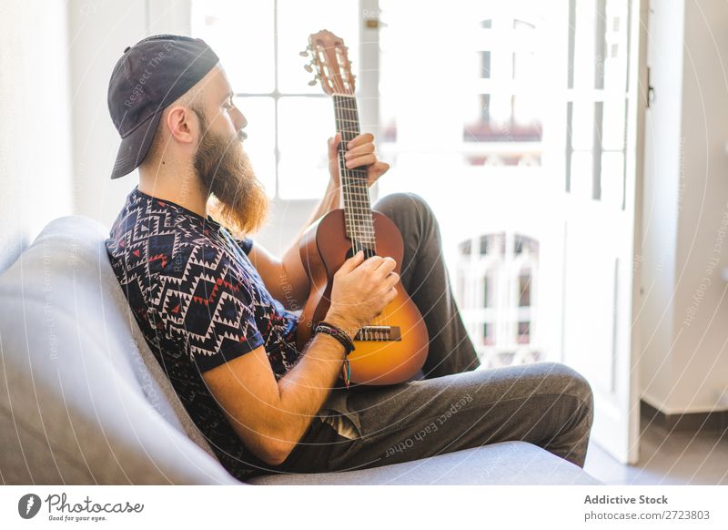 Man playing guitar in armchair Home Relaxation Adults bearded Sit Armchair Playing Guitar Musician Acoustic Easygoing Youth (Young adults)